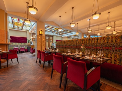 Restaurant Seven Seas is ingericht met elegante tafels, rode fluwelen stoelen en sfeervolle verlichting