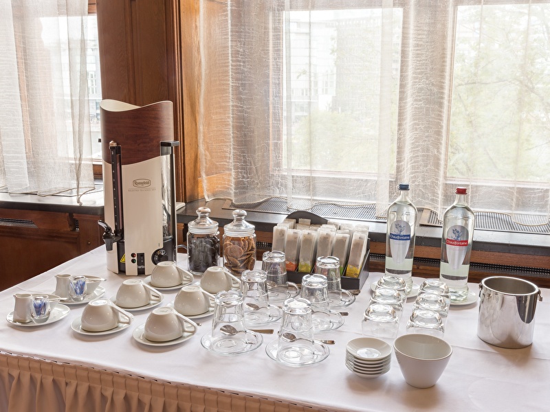 Koffie- en theebuffet in Grand Hotel Amrâth Amsterdam, met een selectie van thee, koffiekopjes, glazen, koekjes en flessen water.